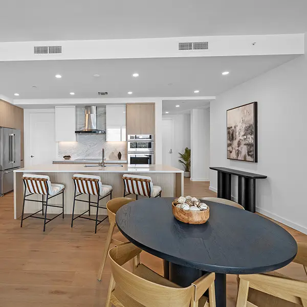 Contemporary condo staging at Bayso Sarasota featuring modern kitchen with island seating, wood cabinetry, and open dining area
