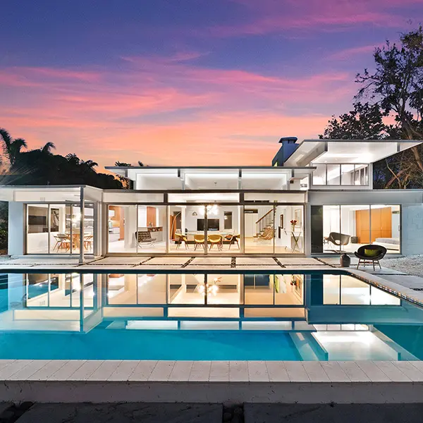 Mid century modern home staging in Lido Shores Sarasota featuring glass architecture, pool reflection, and indoor outdoor living at sunset