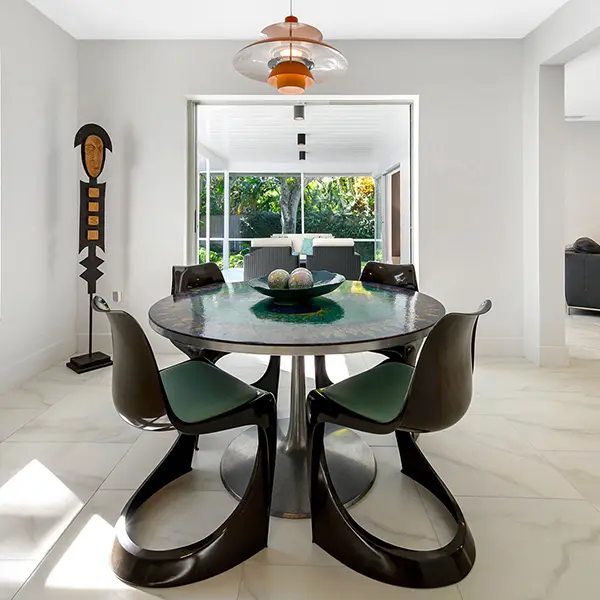 Mid century modern home staging in Siesta Key Sarasota featuring round dining table, sculptural chairs, and bright indoor outdoor connection