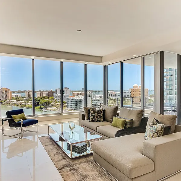 Luxury condo staging at The VUE Sarasota featuring corner living room, floor to ceiling windows, and panoramic bay views