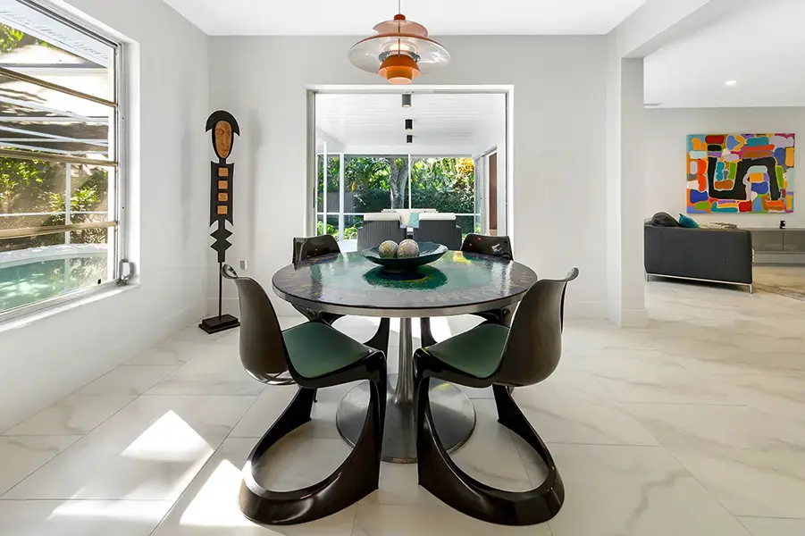 Mid century modern home staging in Siesta Key Sarasota featuring round dining table, sculptural chairs, and bright indoor outdoor connection