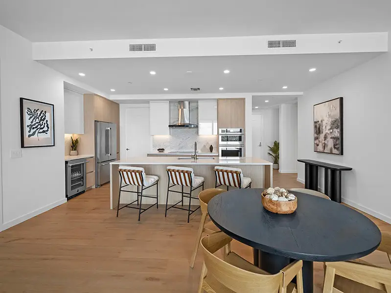 Contemporary condo staging at Bayso Sarasota featuring modern kitchen with island seating, wood cabinetry, and open dining area