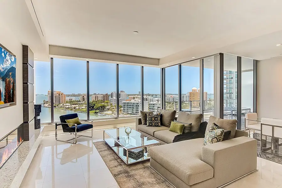 Luxury condo staging at The VUE Sarasota featuring corner living room, floor to ceiling windows, and panoramic bay views