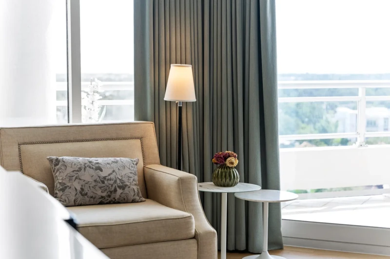 Coastal bedroom seating area with soft textures, floor-to-ceiling drapery, and natural light in Sarasota luxury condo staging