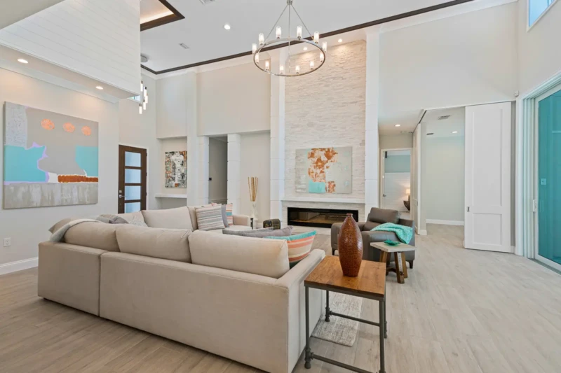 Coastal contemporary living room staging with soaring ceilings and fireplace in Sarasota spec home