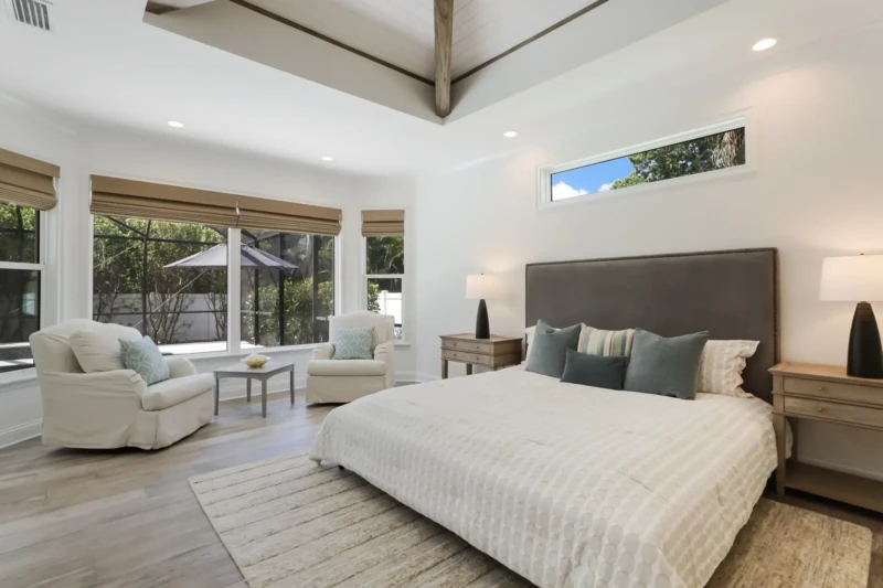 Coastal contemporary primary bedroom staging with vaulted ceiling and pool views in Sarasota luxury home