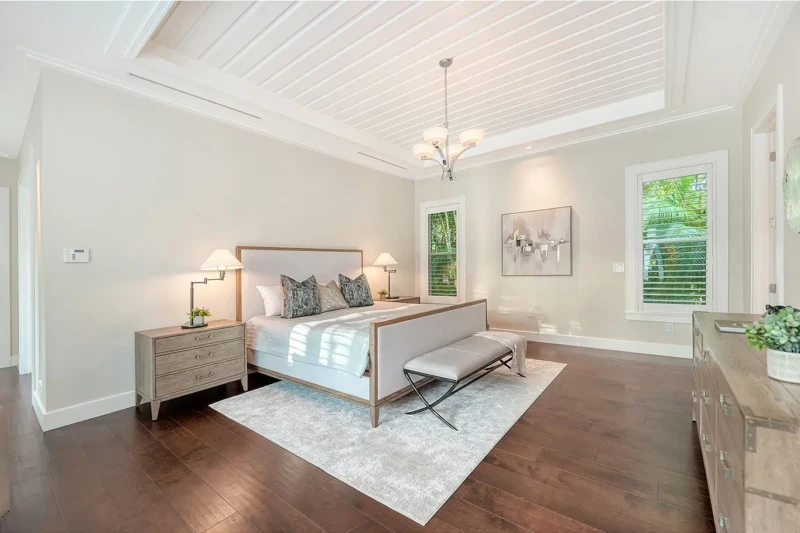 Coastal contemporary primary bedroom staging with tray ceiling and elegant neutral furnishings