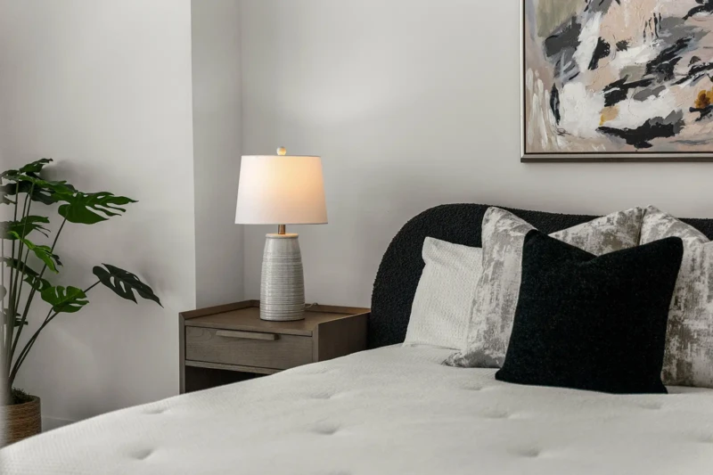 Contemporary bedroom detail with layered neutral bedding, designer accent pillows, and luxury condo staging in Sarasota waterfront residence