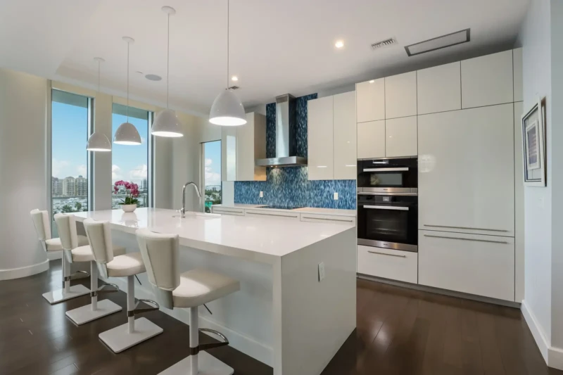 Contemporary luxury condo kitchen staging at The Jewel Sarasota with modern white cabinetry and blue backsplash
