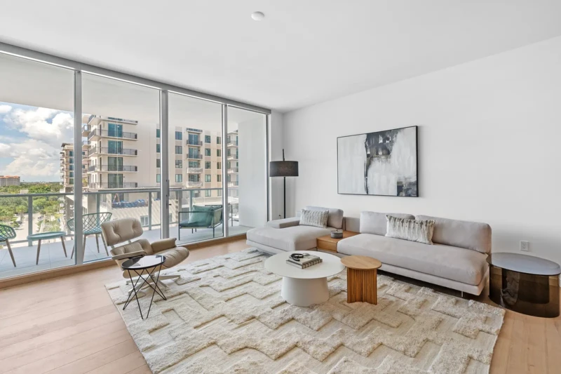 Contemporary condo living room staging with neutral furnishings and balcony