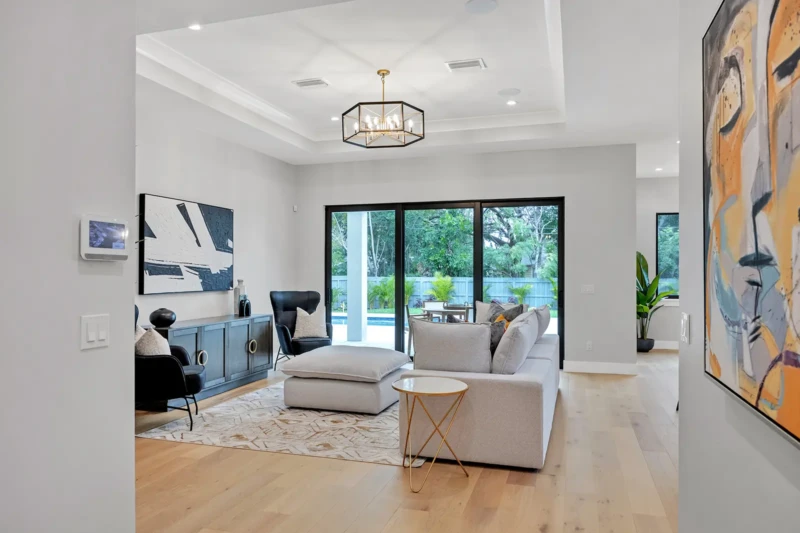 Contemporary living room staging in East of the Trail Sarasota home featuring soft neutral furnishings, modern artwork, and seamless indoor-outdoor luxury living design