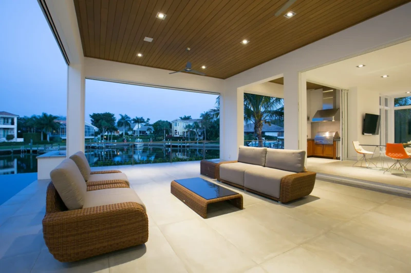 Covered waterfront lanai with modern outdoor seating and canal views in Bay Isles South on Longboat Key at dusk