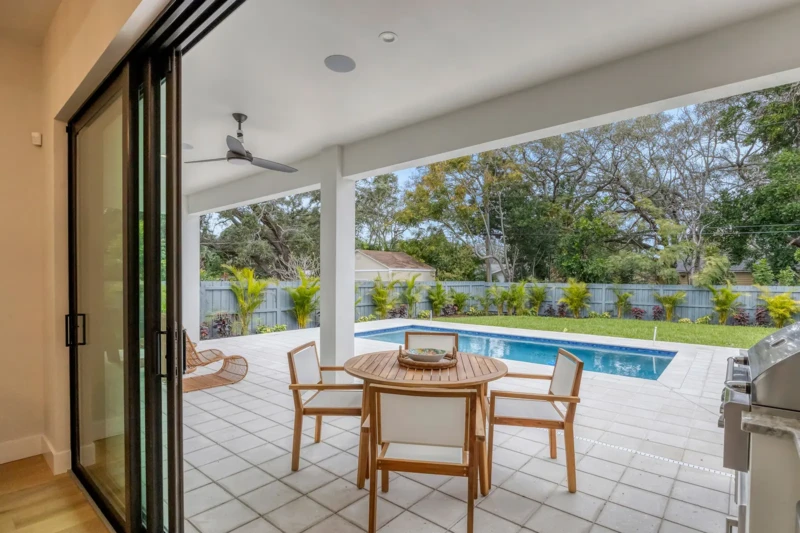 Covered patio and pool area staging in East of the Trail Sarasota home featuring outdoor dining space, modern pool design, and seamless indoor-outdoor luxury living ambiance