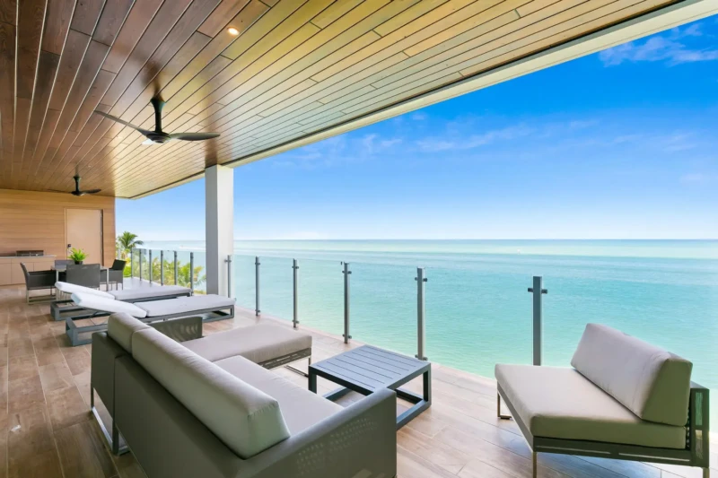 Luxury Gulf-front terrace staging on Siesta Key with panoramic water views, contemporary outdoor lounge seating, and expansive beachfront living space overlooking Sarasota Bay and the Gulf of Mexico