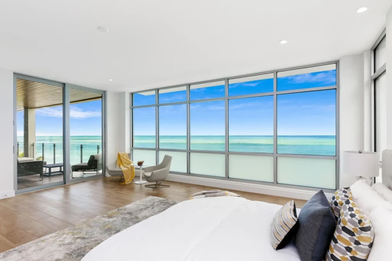 Luxury primary suite staging on Siesta Key with panoramic Gulf views, floor-to-ceiling windows, and coastal contemporary interiors overlooking the water