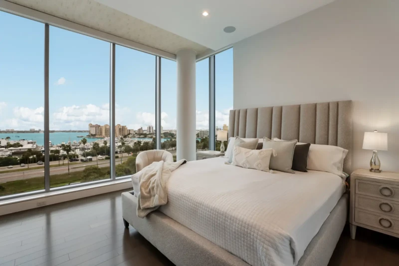 Luxury condo bedroom staging with panoramic bay views at The Jewel Sarasota featuring floor-to-ceiling windows and contemporary furnishings