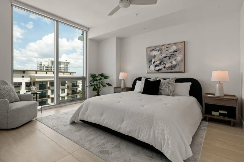 Luxury condo bedroom staging with contemporary furnishings, neutral textures, and floor-to-ceiling windows in Sarasota waterfront residence