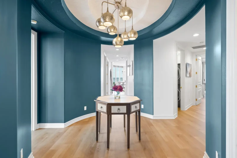 Luxury condo entryway and foyer staging with modern chandelier and blue accent walls in Sarasota condo