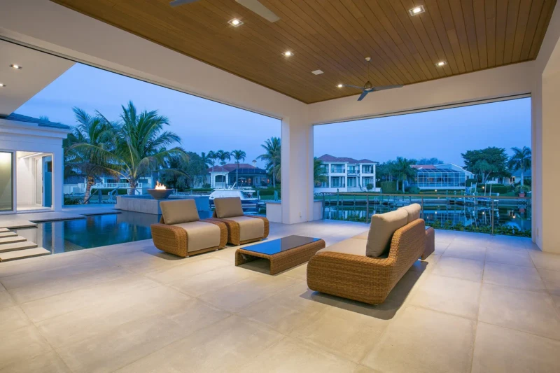 Luxury waterfront outdoor living area with covered lanai and canal views in Bay Isles South on Longboat Key at dusk