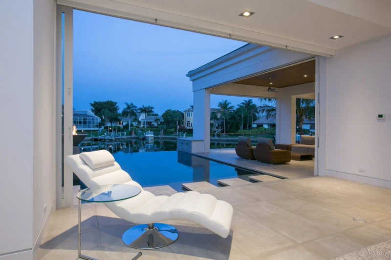 Luxury waterfront home staging with infinity-edge pool and indoor-outdoor living space in Bay Isles South on Longboat Key at dusk