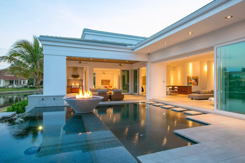 Luxury waterfront pool and indoor-outdoor living space staged in contemporary Bay Isles South home on Longboat Key at dusk
