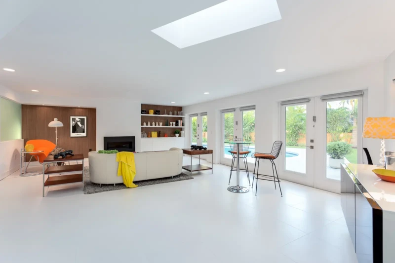 Modern open-concept living room staging in Bird Key Sarasota with bright interiors, white flooring, and poolside access