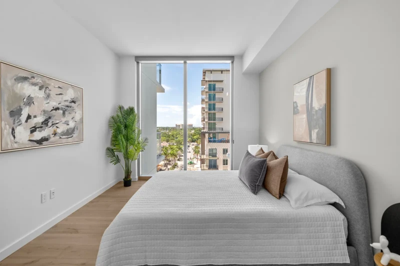 Minimalist condo bedroom staging with floor-to-ceiling windows and neutral decor