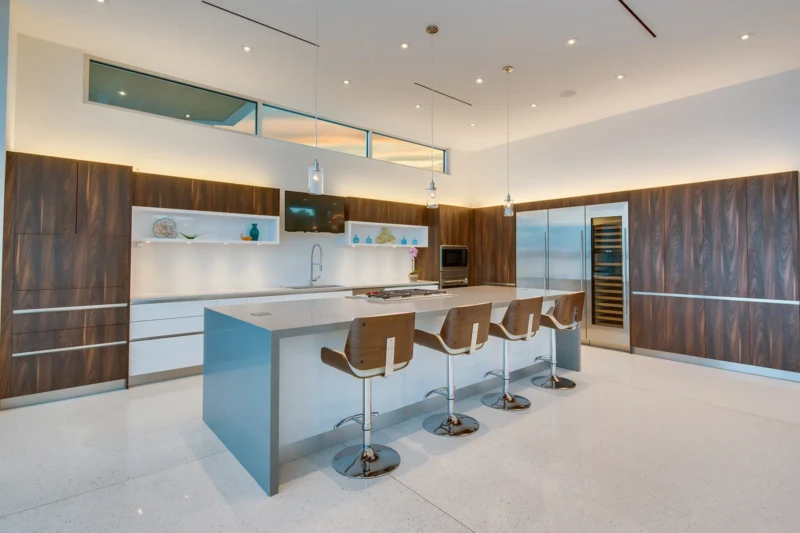 Modern chef’s kitchen staging in Sarasota luxury home with oversized waterfall island, custom walnut cabinetry, and contemporary open-concept design features