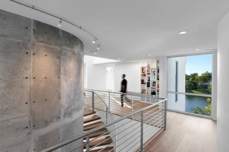Modern floating staircase with exposed concrete wall and waterfront views in luxury Longboat Key home
