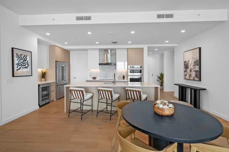 Modern condo kitchen and dining room staging with natural wood accents