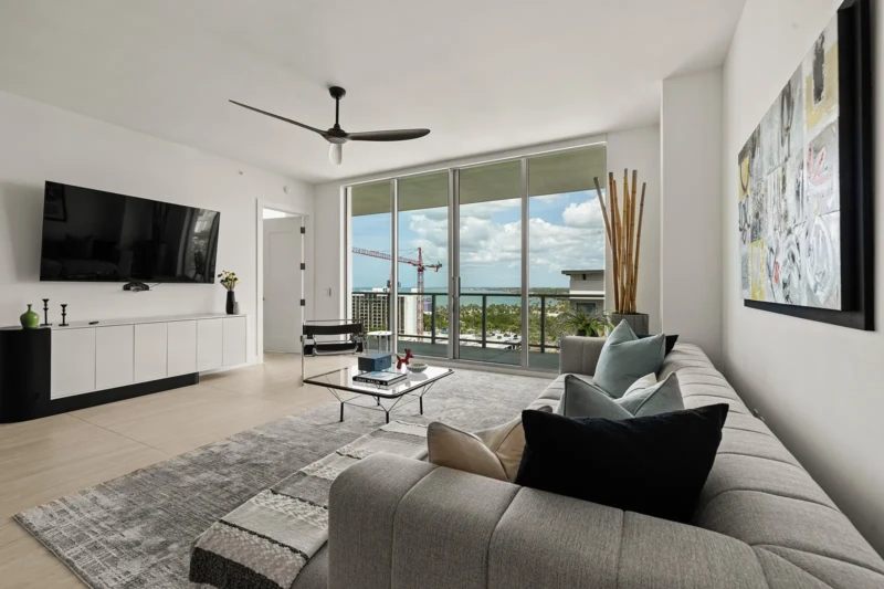 Modern condo living room staging with contemporary sectional sofa, floor-to-ceiling windows, and Sarasota bay views