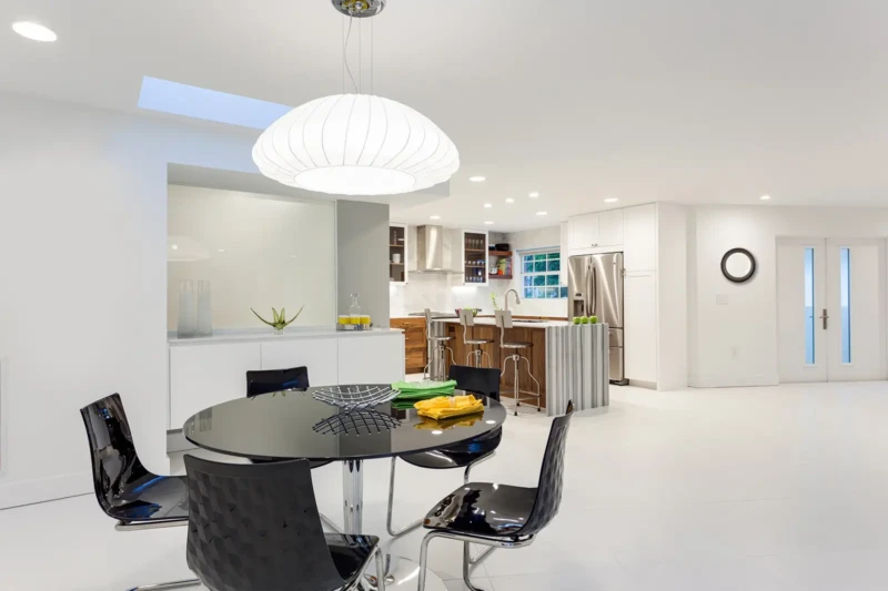 Modern dining and kitchen staging in Bird Key Sarasota with minimalist white interiors, black dining set, and contemporary kitchen design
