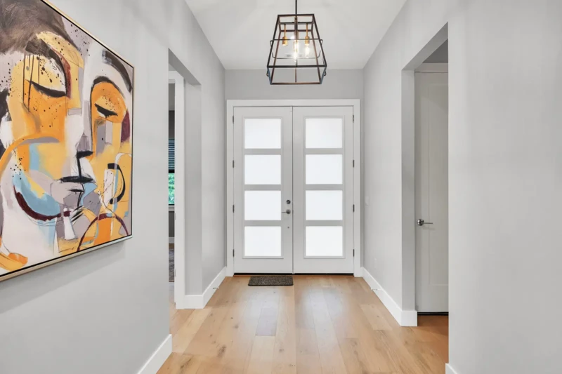 Modern entryway staging in East of the Trail Sarasota home with contemporary artwork, natural wood flooring, and minimalist architectural design