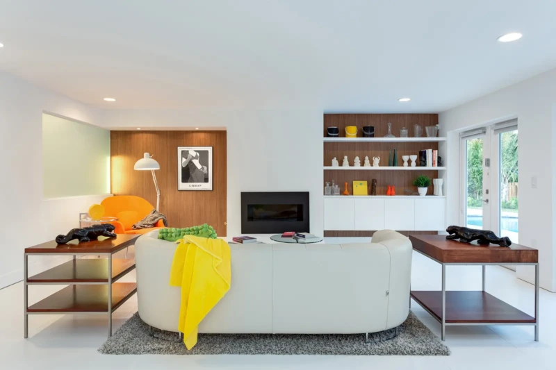 Modern living room staging in Bird Key Sarasota with curved white sofa, custom shelving, and vibrant contemporary accents