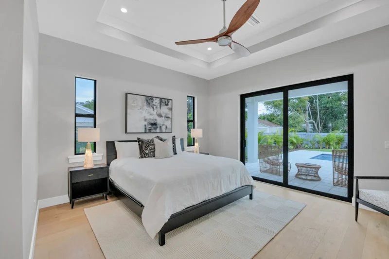 Modern primary bedroom staging in East of the Trail Sarasota home featuring contemporary furnishings, soft neutral tones, and seamless access to covered outdoor living spaces