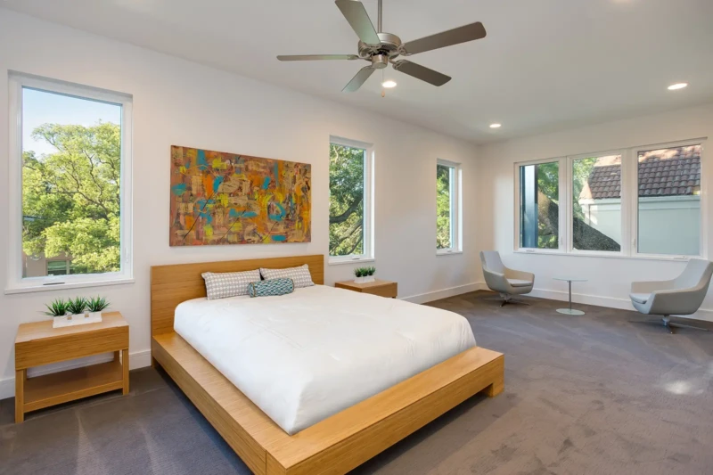 Modern primary bedroom staging with minimalist wood platform bed and sitting area