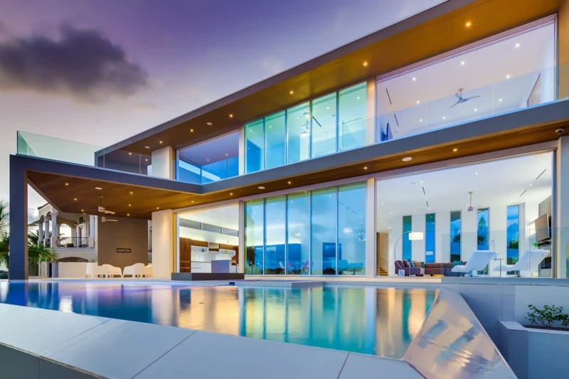 Modern luxury waterfront home staging in Sarasota with expansive glass walls, resort-style pool, and contemporary architectural design at twilight