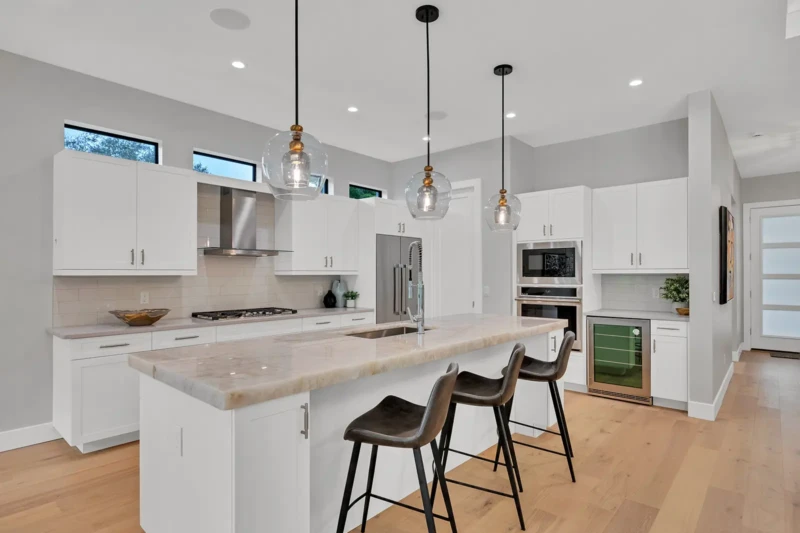 Modern white kitchen staging in East of the Trail Sarasota home featuring waterfall island countertops, contemporary pendant lighting, and luxury open-concept design details