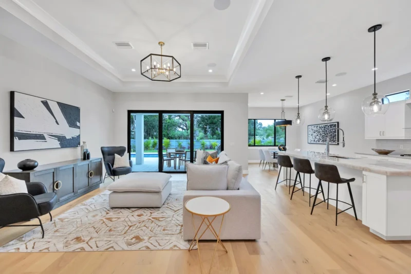 Open-concept kitchen and living room staging in East of the Trail Sarasota home with modern island seating, contemporary furnishings, and seamless indoor-outdoor living design