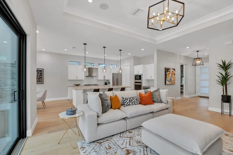 Open-concept living room and kitchen staging in East of the Trail Sarasota home featuring contemporary furnishings, light wood flooring, and modern coastal-inspired interior design