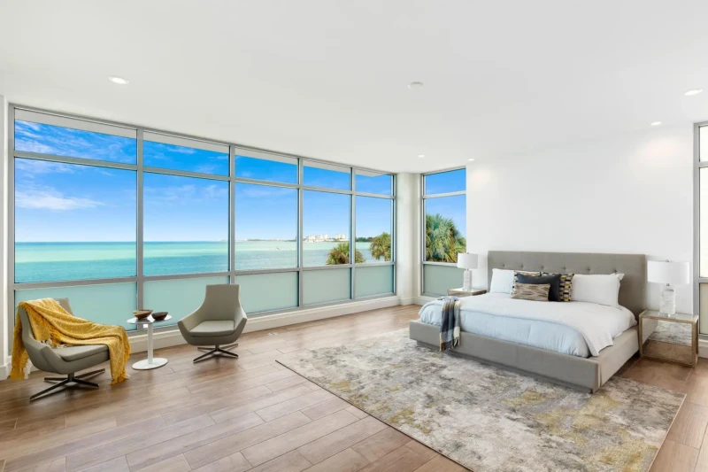 Waterfront primary bedroom staging on Siesta Key featuring panoramic Gulf views, floor-to-ceiling windows, and luxury coastal contemporary design